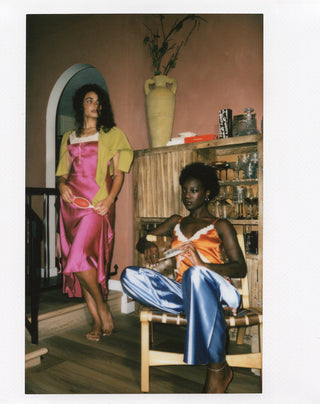 Two women in satin slips with Greedy brushes, in a Polaroid frame